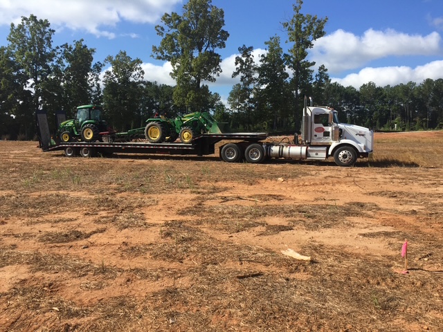 Kenworth lowboy hauling John Deere tractors to a job site