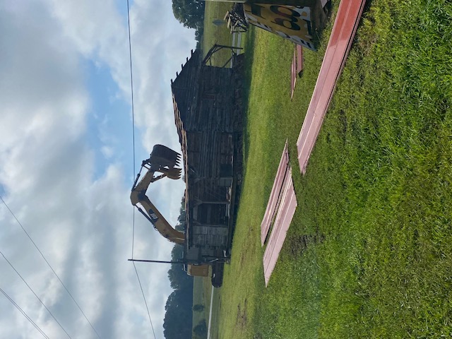 Excavator demolishing an old timber structure